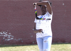 A young girl standing outside holds open a film clap board