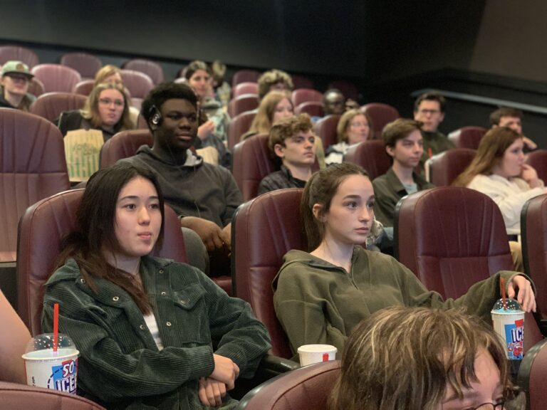 Middle school students sit in darkened movie theater