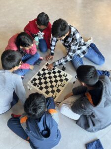 6 children huddle around a practice chess board, immersed in the game