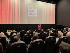 CEO Carolina Thor stands toward an attentive audience sitting in the theater